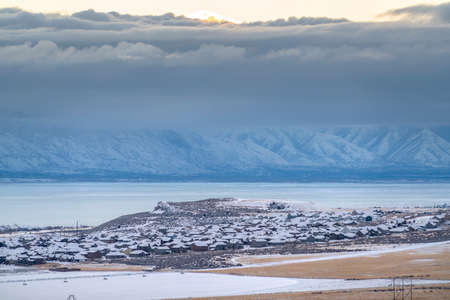 Scenic utah valley landscape with snowy mountain frozen lake and frosted houses. The golden sun in...