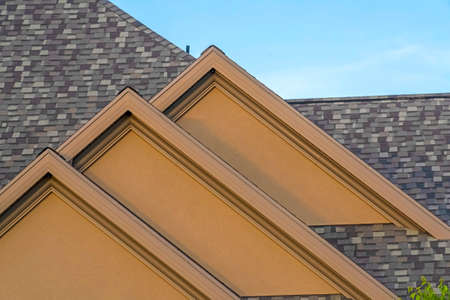 House exterior with front gable roof design against blue sky background. Close up view of the...