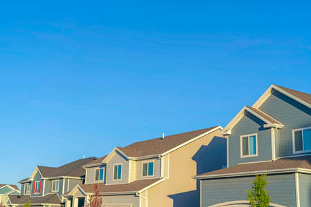 Homes with horizontal wall sidings and front gable roofs againts clear blue skyの写真素材