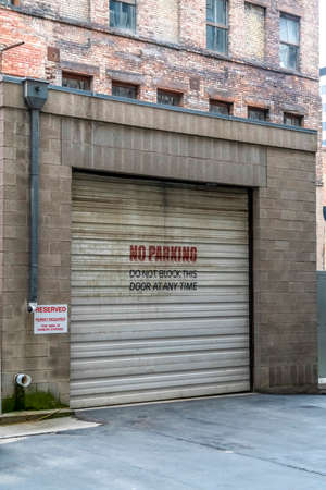 Corrugated metal garage door of an old brick building with No Parking sign. Entrance to the garage...