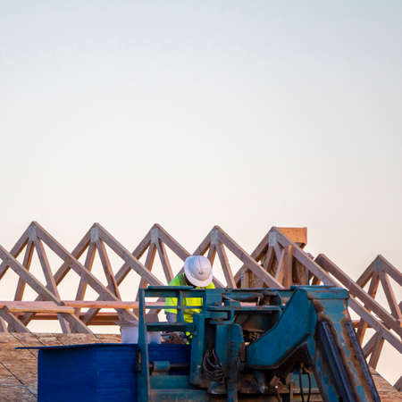 Square Builder or roofer using a mechanical arm to install a roof on a new build house in a close up...