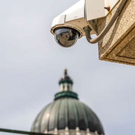 Square frame Outdoor dome security cctv camera with Utah State Capital Building background. View of a secured building exterior and famous dome in Salt Lake City against cloudy sky.の写真素材