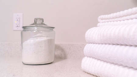 Panorama crop Folded white towels and glass jar with white powder on the bathroom countertopの写真素材