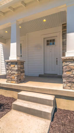 Vertical Yard pathway and steps that leads to concrete porch and white front door of home