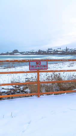Vertical frame Scenic Utah Lake in winter with No Trespassing sign a fence in the foreground