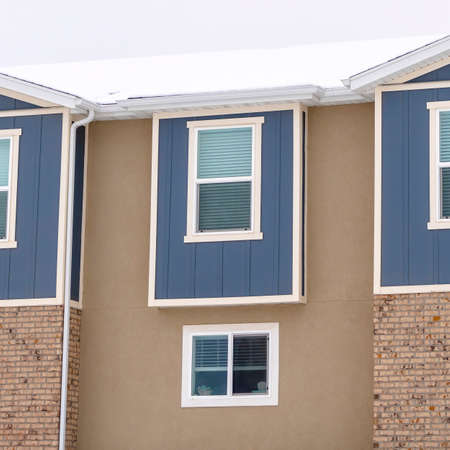 Square Townhome exterior with sliding glass windows brick walls and vertical sidingsの写真素材