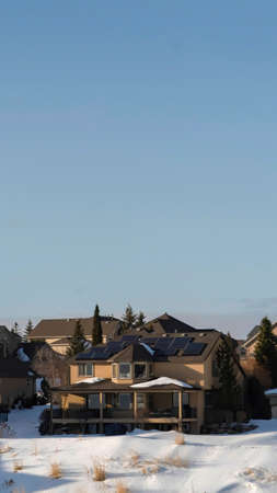 Vertical Vast gray sky over homes on the snowy slope of Wasatch Mountains in winter. The luxurious houses has a wonderful view of frosted scenic landscape.の写真素材