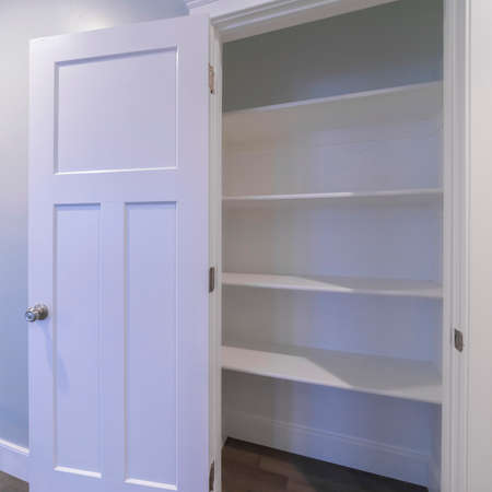 Square Open empty fitted cupboard or wardrobe with white wooden shelves in an interior wallの写真素材