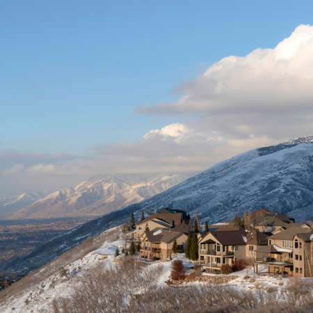 Square Homes on a mountain slope in Utah with breathtaking Wasatch Mountains view. The vast valley and cloudy blue sky can also be seen in this winter scenery.の写真素材