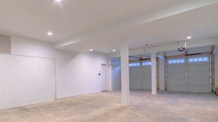 Panorama Large empty concrete garage interior lit by down light looking to double automated doorsの写真素材