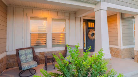 Panorama crop Home with outdoor steps that leads to the gabled entrance and front porch. Wooden front door with glass panes and wreath can also be seen at the facade of this house.の写真素材