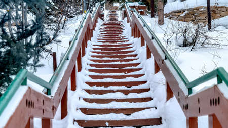 Panorama crop Focus on stairway that goes up a snowy hill with residential homes in winter