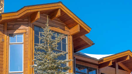 Panorama crop Sunny winter day in Park City Utah with view of home featuring large bay windows