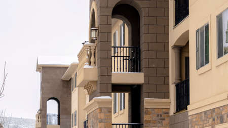 Panorama frame Facade of lovely apartments with snowy yard and roofs against cloudy winter sky....