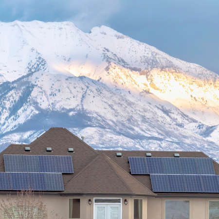 Square frame Solar panels on roof of home with lake and snowy mountain background in winterの写真素材