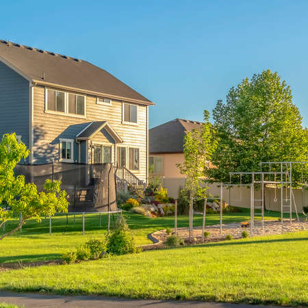 Square Pathway amid grassy terrain in front of neighborhood homes under sunny blue sky. Scenic residential landscape with abundant green foliage and nature views.の写真素材
