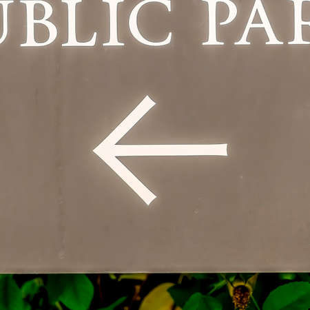 Square No Public parking sign with arrow at the Receiving area outside a building. Close up view of a building signage with vibrant green leaves in the background.の写真素材
