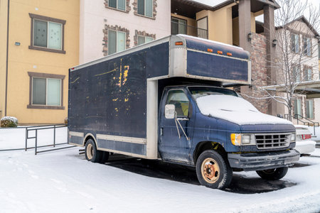 Small freight delivery truck in a snowy parking lot of a neighborhood in winterの写真素材