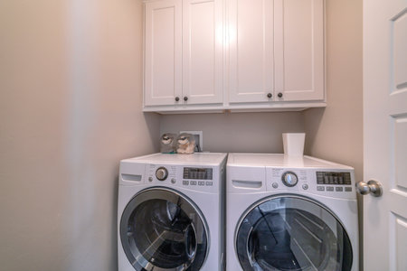 Interior of laundry room with appliances and wall mounted wooden cabinetの写真素材