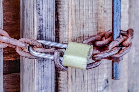 Close up of closed old outdoor bathroom door with padlock and rusty metal chainの写真素材