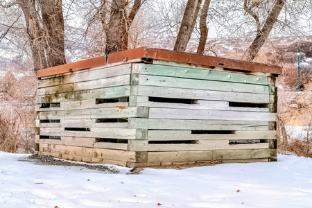Flat roof shed on snow covered hill with thriving leafless trees in winterの写真素材