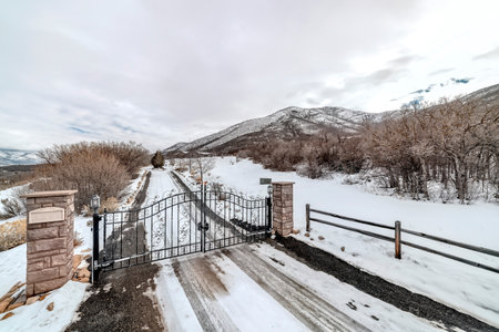 Road with iron gate in the mountain blanketed with snow on a cloudy winter day