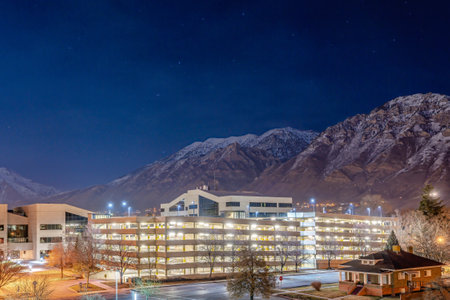Buildings and parking lot against rocky mountain and dark blue sky at night timeの写真素材