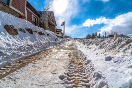 Snowy road with tire tracks of vehicles on a frosted neighborhood in winterの写真素材