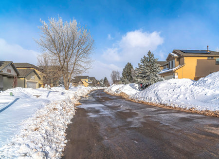 Neighborhood views with paved wet road and houses on a snowy winter settingの写真素材