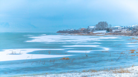 Utah Lake in winter with snow and ice over freshwater surface against cloudy sky
