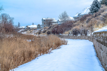Homes overlooking snowy trail along the shore line of Utah Lake under cloudy skyの写真素材