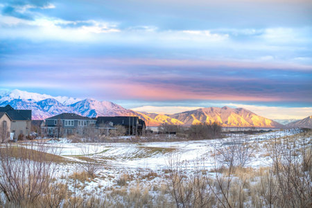 Sunset scenery with houses in the snowy valley overlooking lake and mountain.