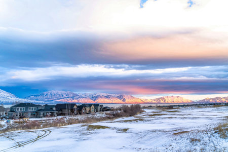 Panorama of a scenic valley in winter with houses lake and sunlit mountain viewsの写真素材