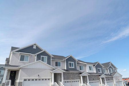 Beautiful townhouses with entrance stairs and white garage doors against sky