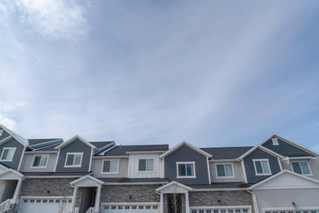 Front view of two storey townhouses in the suburbs against clouds and blue skyの写真素材