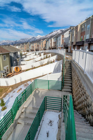 Homes and townhouses with snowy mountain peak and cloudy blue sky in winterの写真素材