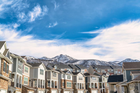 Beautiful houses in Utah Valley against snowy mountain peak and cloudy blue skyの写真素材