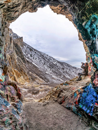 Photographer under natural stone arch formation in scenic Provo canyon Utah