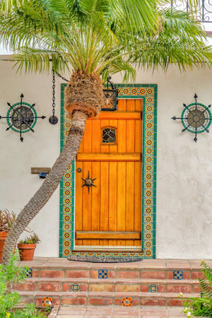 Brown wooden front door framed with decorative tiles in Long Beach Californiaの写真素材