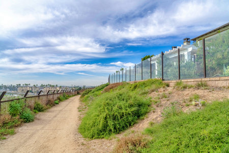 Narrow trail pathway under cloudy blue sky in Huntington Beach California