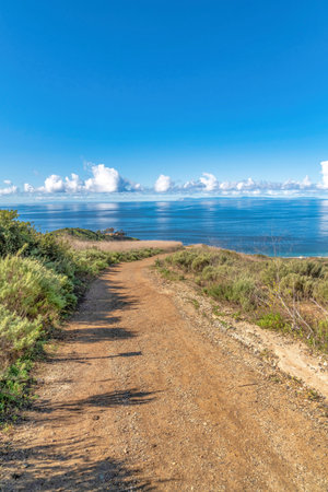 Dirt trail path overlooking blue sea and cloudy sky at Laguna Beach Californiaの写真素材