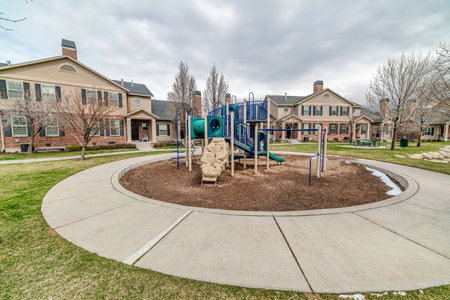 Playground in the neighborhood park surorunded by houses and circular pathwayの写真素材