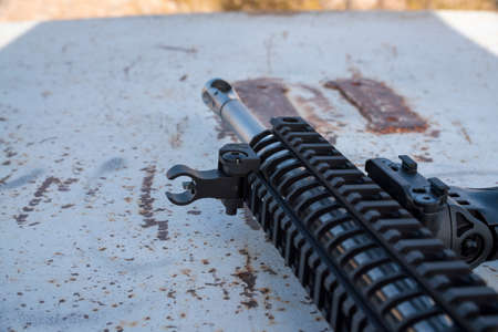 Close up of a metal black rifle with mount holding a scope