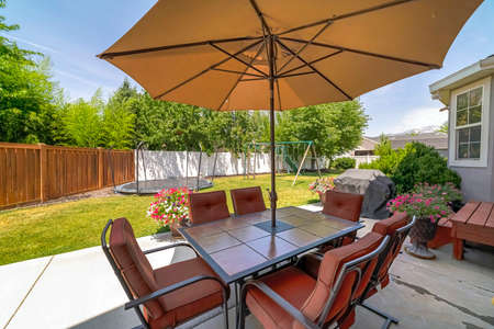 Patio at a home backyard with trampoline and playground on the vibrant lawnの写真素材