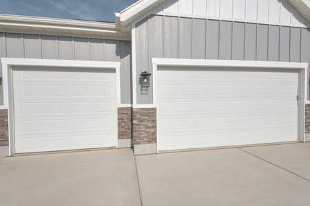 Two car garage exterior view of residential house with gabled roof and gray wall