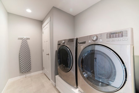Light gray laundry room with tiles, washer, dryer and storage roomの写真素材