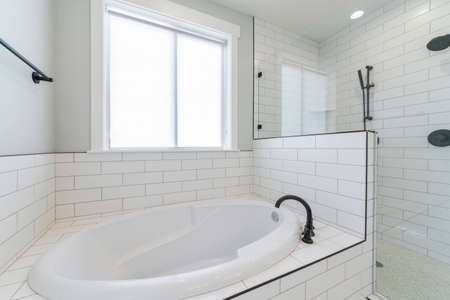 White bathroom interior with window, drop in tub and shower stallの写真素材