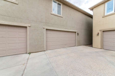 Exterior of two buildings with concrete driveway, garage doors and windowsの写真素材