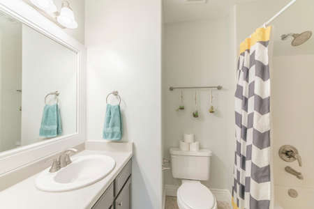Small bathroom with wooden vanity sink and shower stall with patterned shower curtainの写真素材