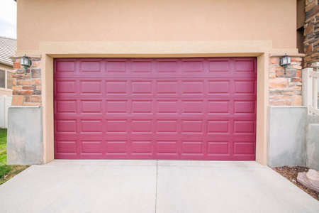 Burgundy closed garage door with two wall lamps on a brick wallの写真素材